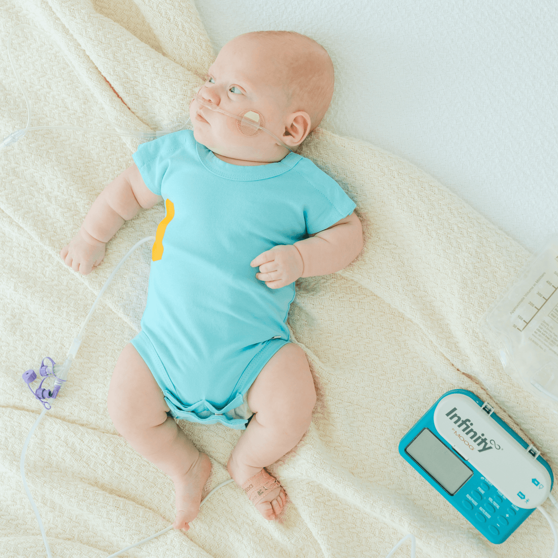 baby-wearing-tube-eeze-patch-on-a-blue-onesie,-showcasing-adaptive-clothing-for-feeding-access.