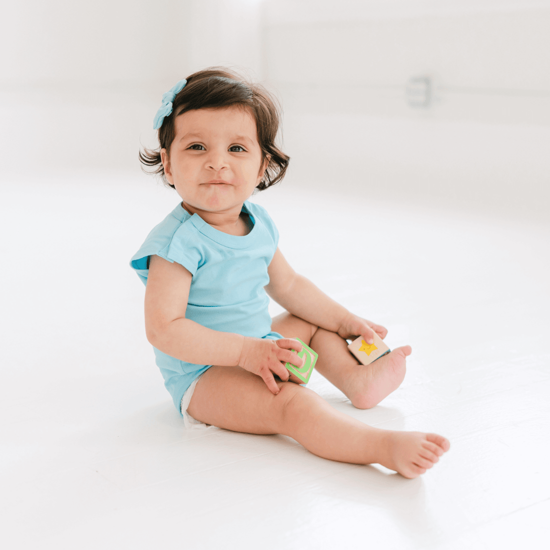 happy-baby-in-a-blue-bodysuit-playing-with-toys-on-a-bright-floor,-showcasing-the-baby-starter-set-features.