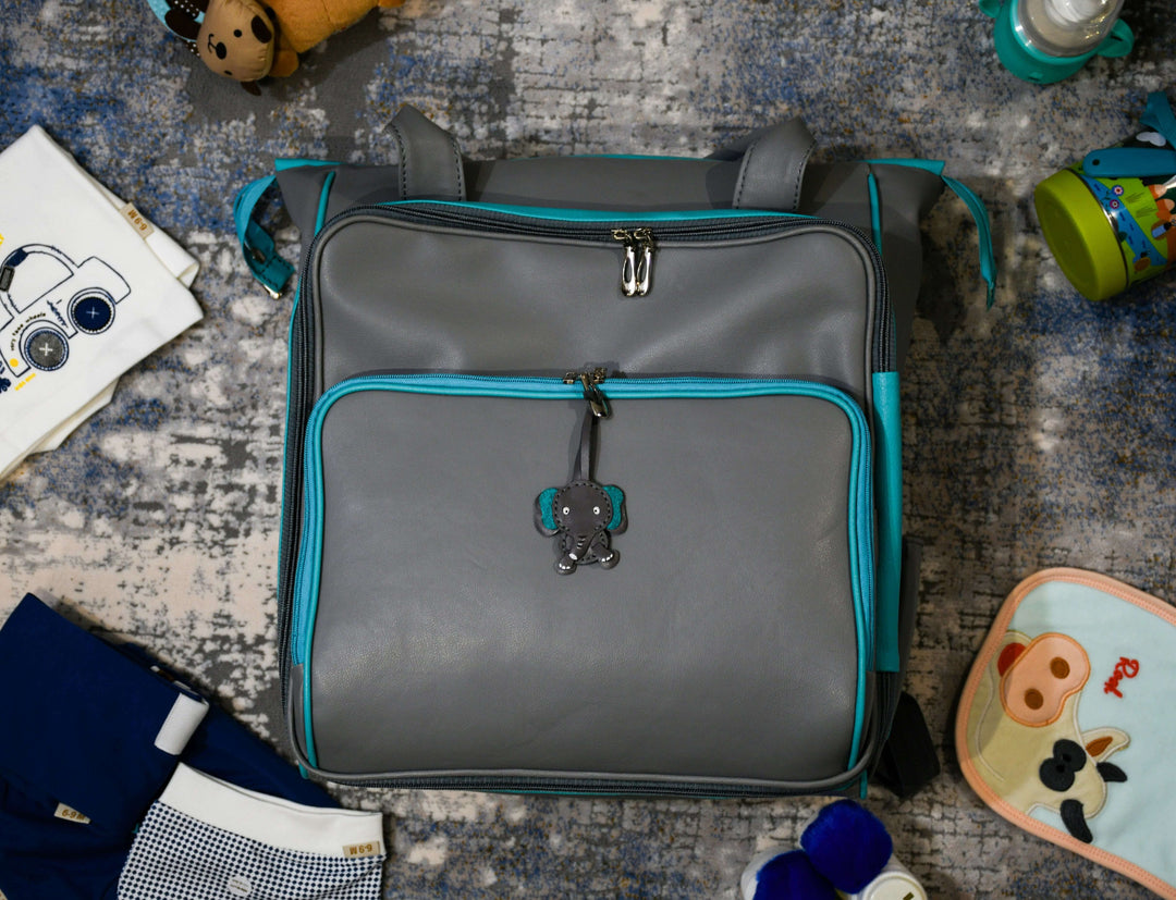 Stylish gray hospital bag with turquoise accents, surrounded by baby items and essentials for packing.