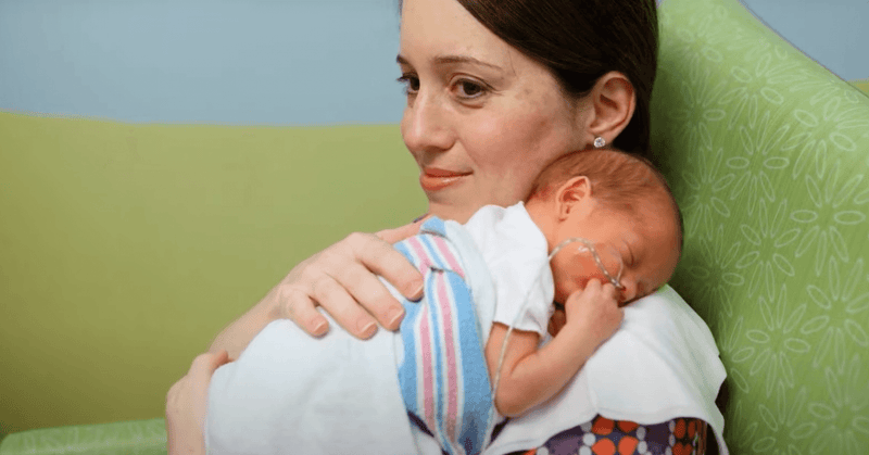 Mother holding her premature baby in the NICU, showcasing love and support during a challenging time.