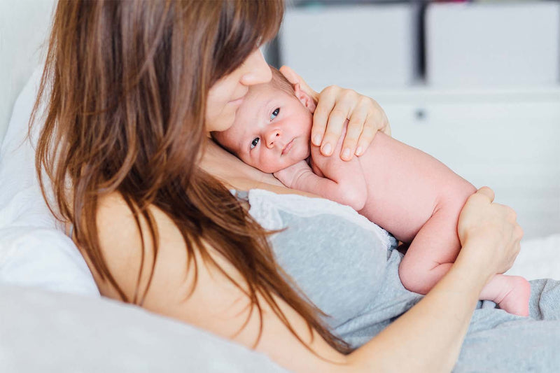 Mother holding newborn in a skin-to-skin position, showcasing the concept of Kangaroo Care.